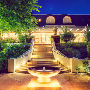 Le Franschhoek Hotel & Spa front stairs lighted and a small fountain