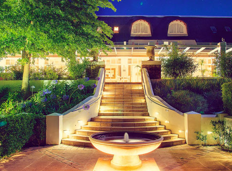 Le Franschhoek Hotel & Spa front stairs lighted and a small fountain