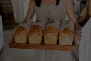 woman carrying a tray with 4 baked breads